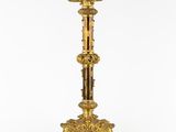 a gold plated candle holder with a candle on a stand
