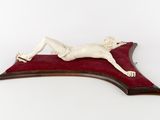 a statue of a person laying on a red piece of cloth