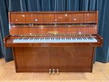 a piano that is sitting on the floor in front of a curtain