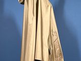 beige raincoat on a mannequin stand against a blue background