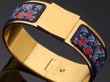 a close up of a gold bracelet with a blue and red design