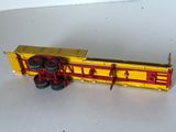 un camion jouet jaune et rouge posé sur une surface blanche