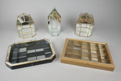 quatre objets en verre et en métal posés sur une surface blanche