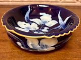 a blue bowl with white flowers on it sitting on a table