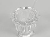 an empty glass ashtray with a spoon in it on a white surface