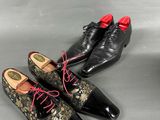 two pairs of black and gold shoes with red laces