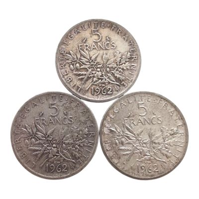 trois pièces d'argent posées l'une sur l'autre sur une surface blanche