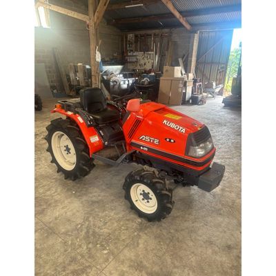 un tracteur rouge garé dans un garage avec un gros pneu