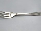 a close up of a fork on a table with a gray background
