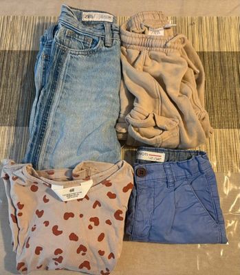 trois paires de jeans et un t-shirt posés sur un lit