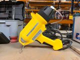 un pistolet à colle électrique jaune et noir posé sur une table