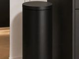 La poubelle noire se trouve à côté de l'armoire noire dans la cuisine.
