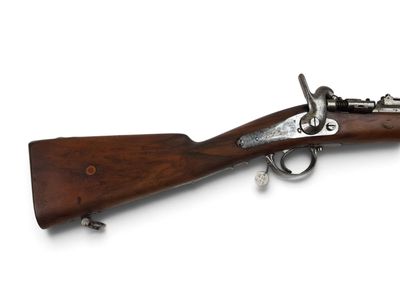un vieux fusil exposé sur une surface blanche