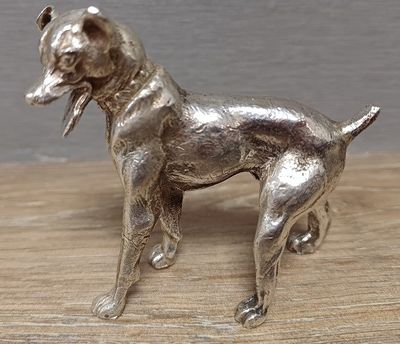 figurine de chien en argent posée sur une table en bois, sur fond gris