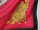 a close up of a red and black scarf with a gold crest on it