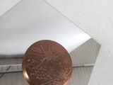 un petit miroir posé sur une table, avec une pièce de un penny dessus