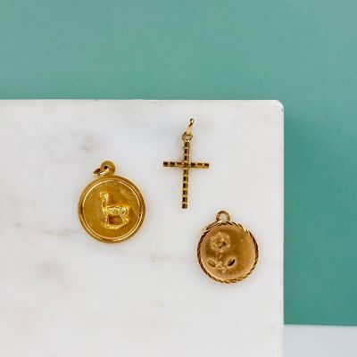 un gros plan d'une croix en or et d'un cachet de cire doré posés sur une dalle de marbre