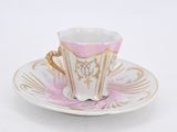 a close up of a cup and saucer on a white surface