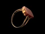 a close up of a gold ring with a red stone in it