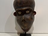 sculpture of a man ' s head on a stand in front of a white wall