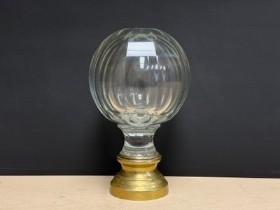 une image représentant un vase en verre avec un socle doré posé sur une table