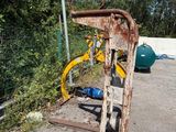 a rusted bike leaning against a fence in a parking lot