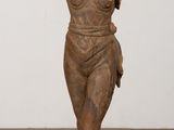 statue of a woman standing on a wooden base on a wooden floor