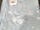 une chemise à carreaux bleus et blancs dans un sac en plastique posé sur une table en bois