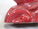 a close up of a red vase on a white surface