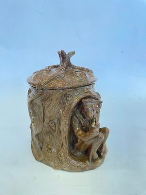 une image représentant une figurine en céramique d'un ours dans un tronc d'arbre