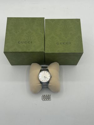 un gros plan d'une montre avec son coffret posée sur une surface blanche