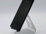 a black cell phone on a stand on a white surface