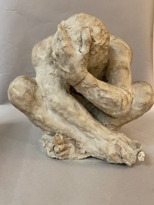 a sculpture of a man sitting on a piece of wood