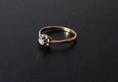 a close up of a gold ring with a diamond on a black surface