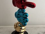 a sculpture of a hand holding a ball on top of a table