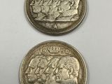 two silver coins, one of which has a face and the other of which is a head