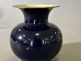 un vase bleu à bord doré posé sur une table