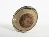 un gros plan d'un bol marron et bleu posé sur une surface blanche