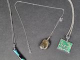 trois bijoux sont exposés sur un fond noir