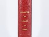 un vieux livre rouge posé sur une table à côté d'un mur blanc