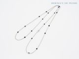 deux longs colliers de perles noires et blanches sur fond blanc