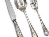 three silver spoons and a knife on a white surface