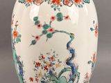 a white vase with a bird and flowers on it