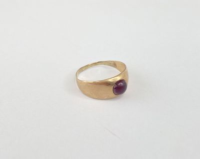 a close up of a gold ring with a red stone