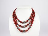 un collier composé de perles rouges et d'argent sur un mannequin blanc
