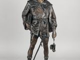 a bronze statue of a man with a hat and a cane