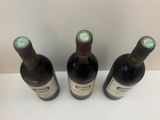 trois bouteilles de vin posées sur une table, l'une à côté de l'autre