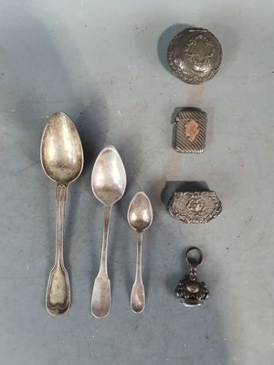plusieurs cuillères en argent et un repose-cuillère posés sur une table à côté d'un rocher