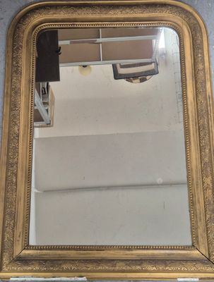 un miroir à cadre doré accroché au mur, avec une étagère en dessous