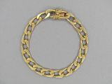 gros plan d'un bracelet en or sur une surface grise